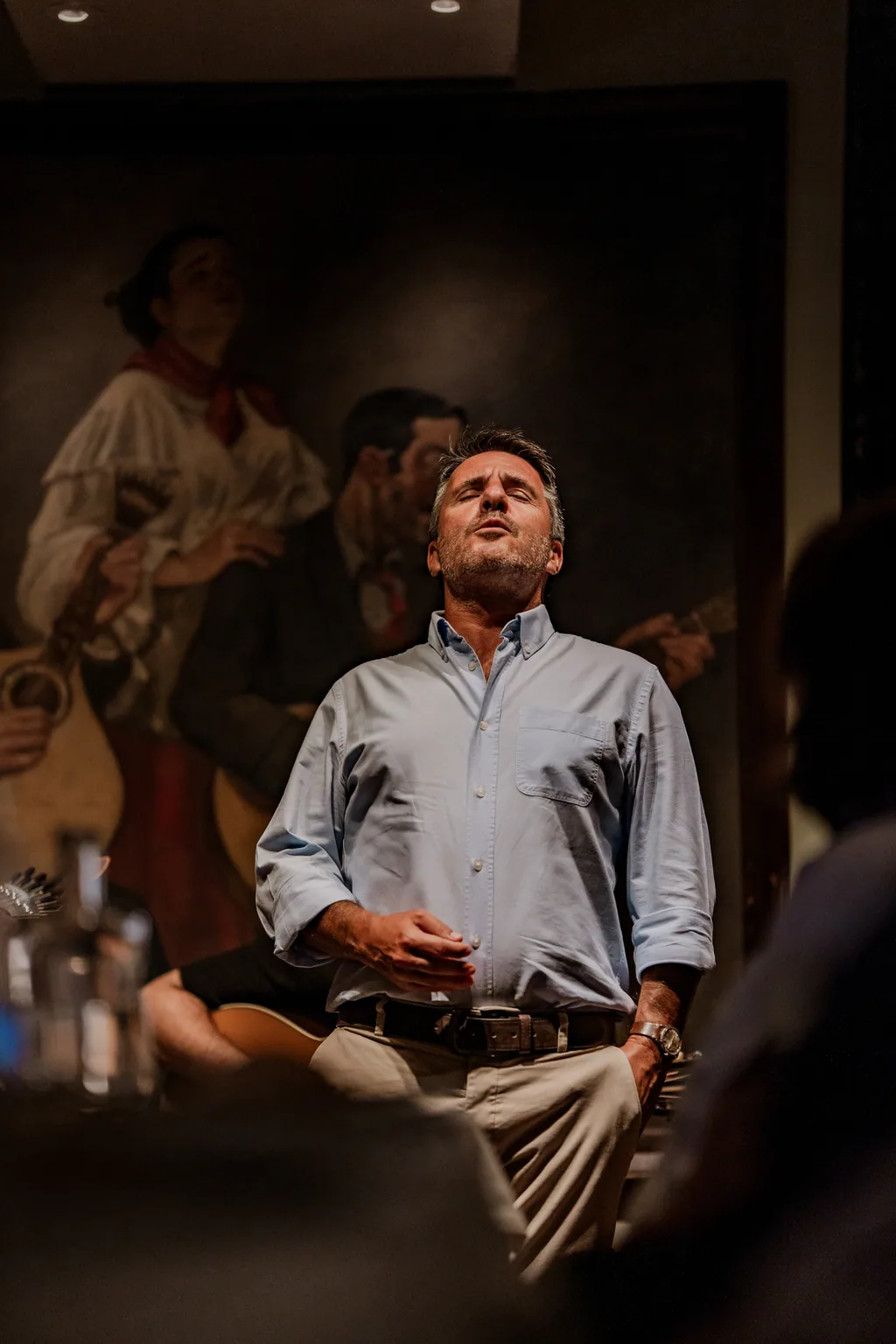 Fadista a cantar de olhos fechados na sala da Adega Machado, diante da pintura de fadistas antigos